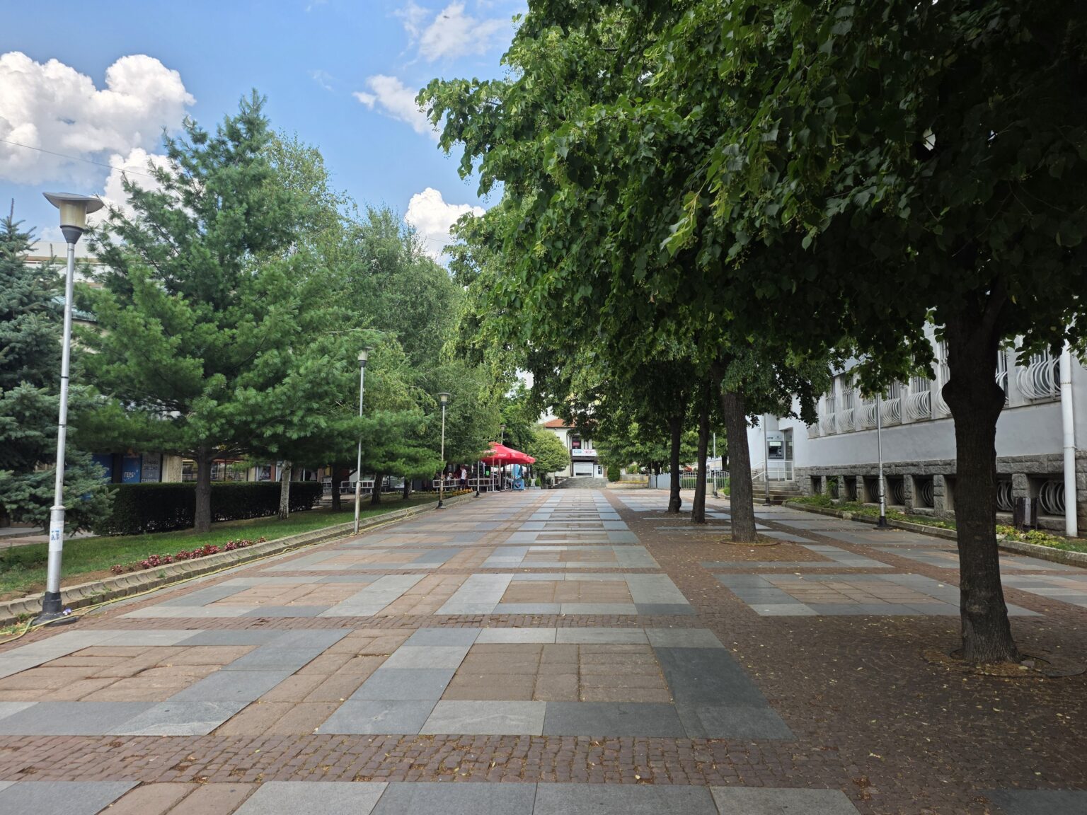 A wide pedestrian zone with slab paving and trees in the centre of Dupnitsa