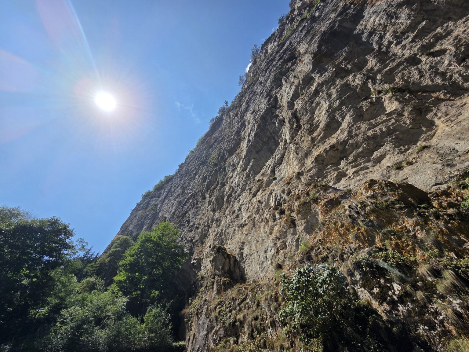 Bright sun shining over sheer stone cliffs