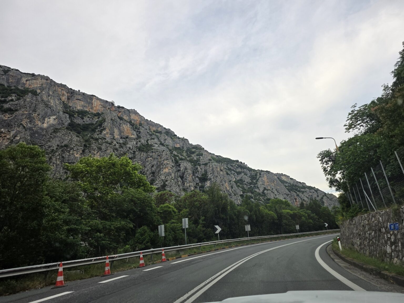 Asphalt road with protective barriers alongside high rocky hills