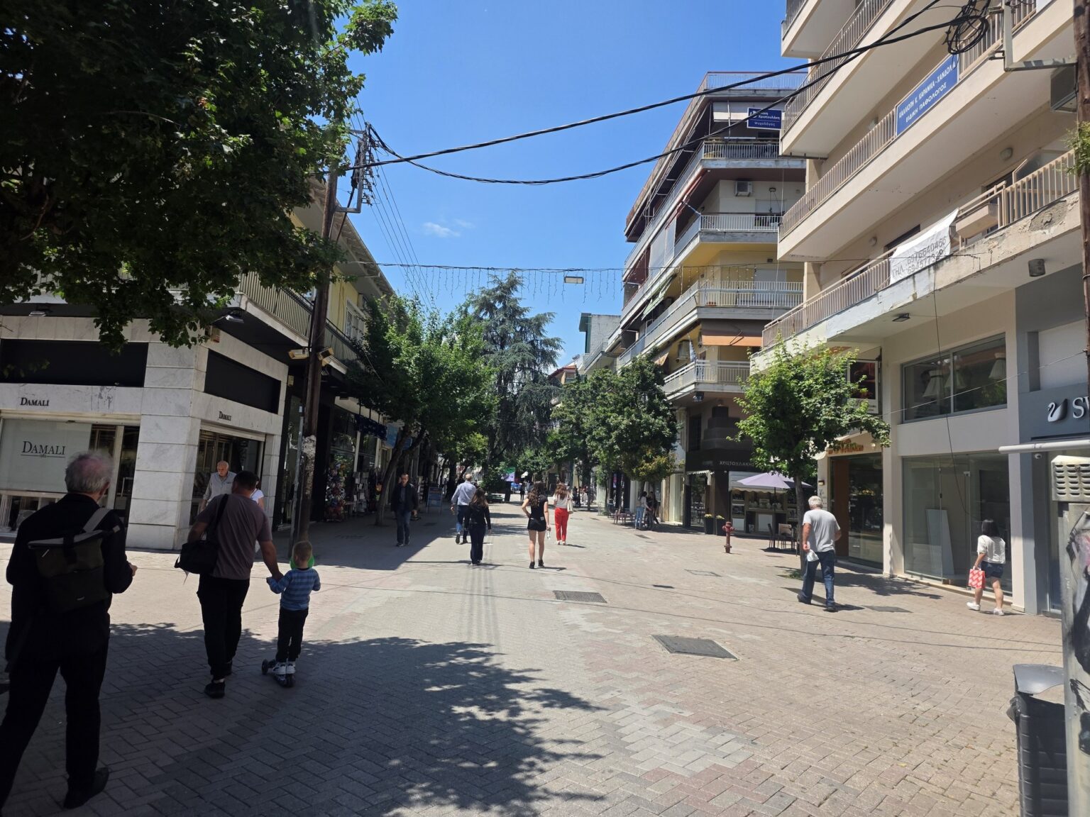 Pedestrians and buildings along a busy city street on a sunny day