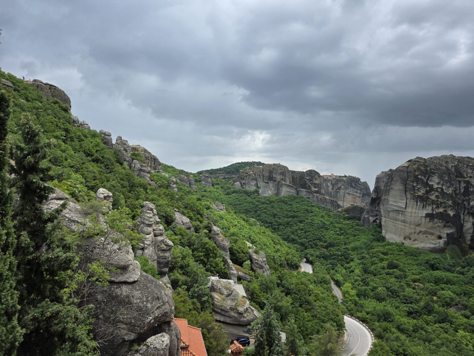 Winding asphalt road among green forests and tall rocks