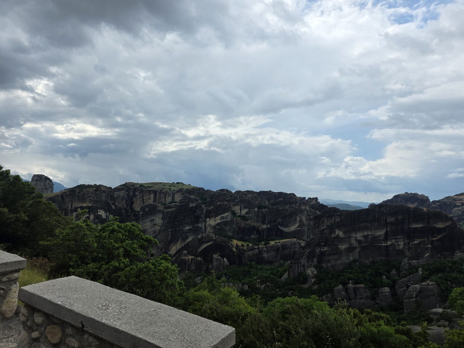 Rock massifs with wooded hills under a cloudy sky from the road