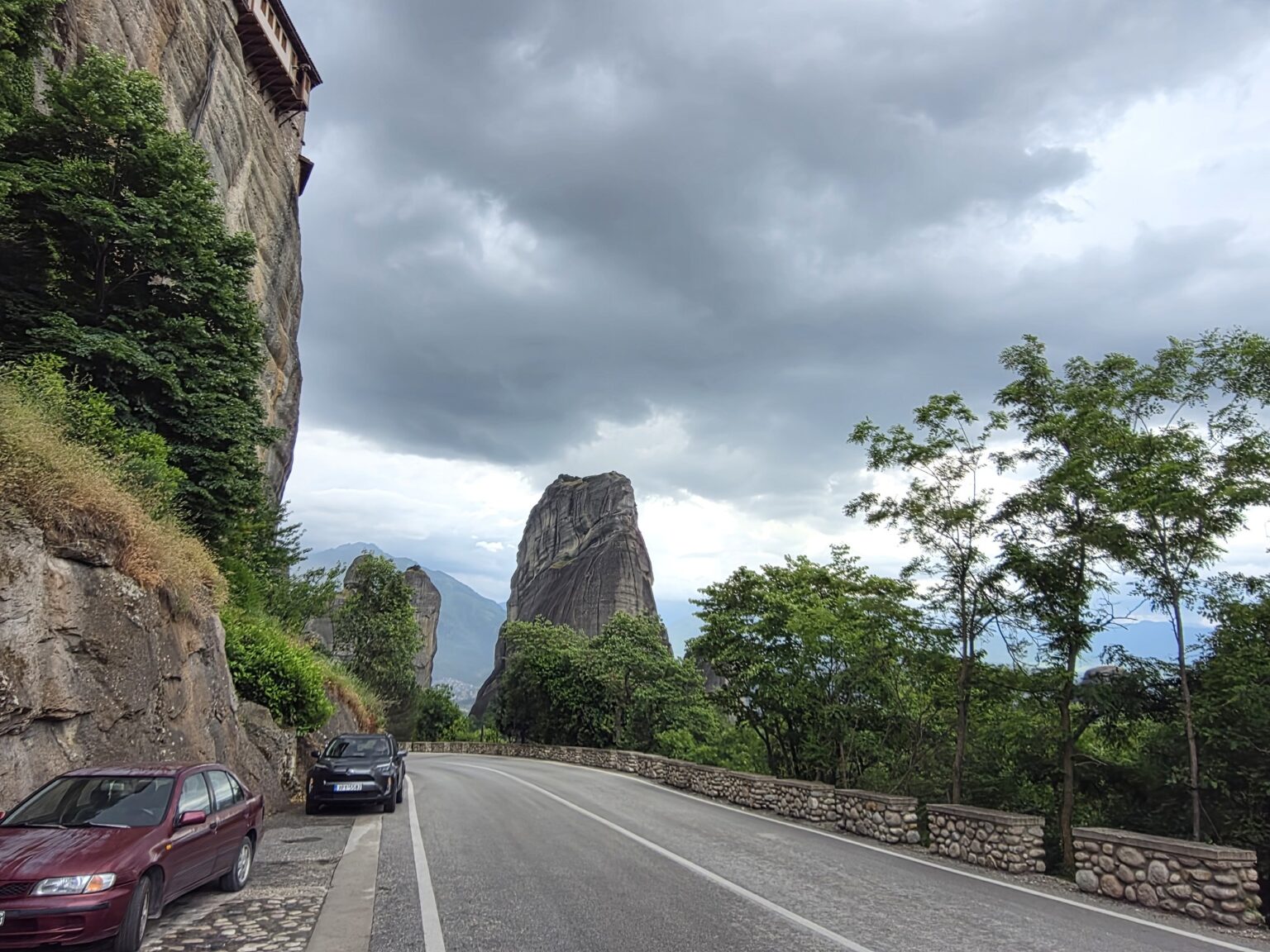 winding asphalt road along high cliffs and greenery