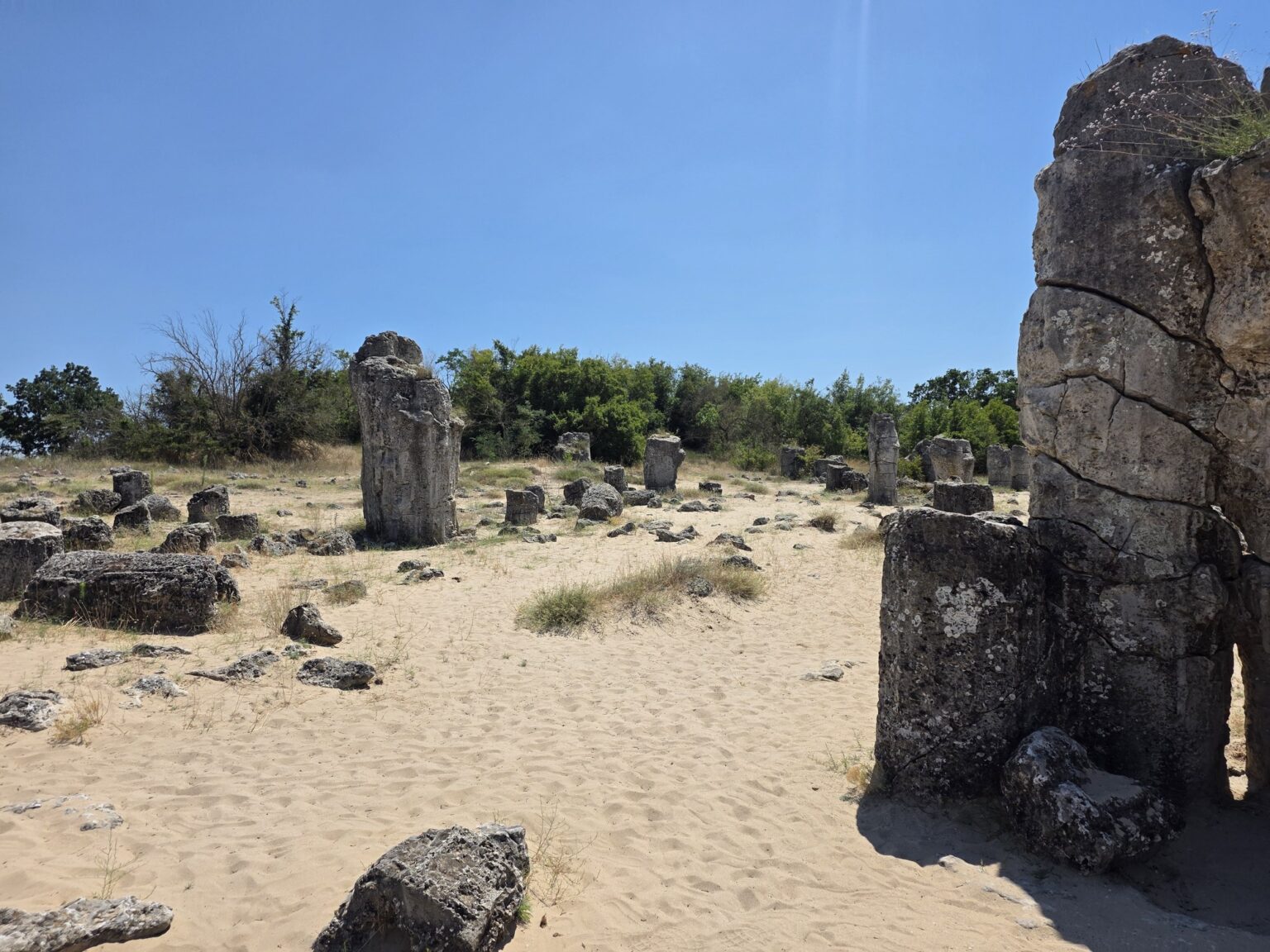High stone column in the foreground of the sandy area