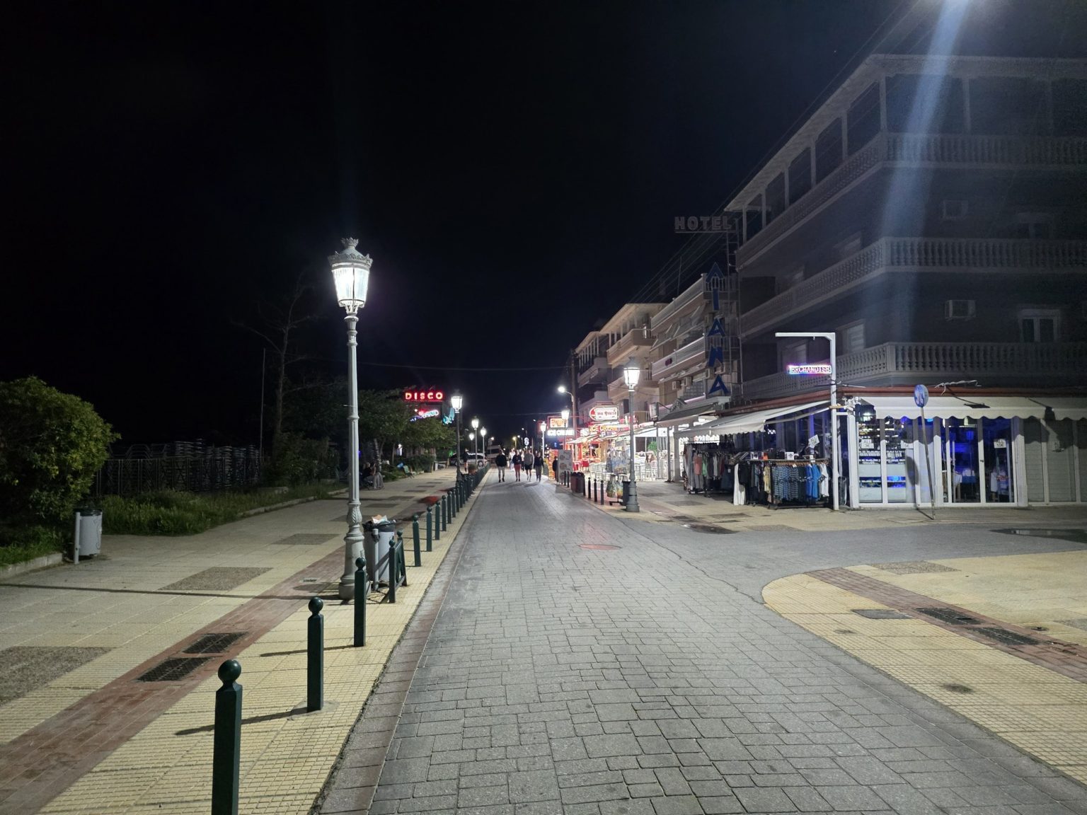 Павената алея с лампи и сгради през нощта
